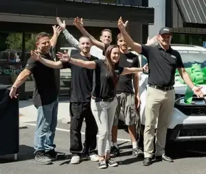 Better Collision team standing with arms raised