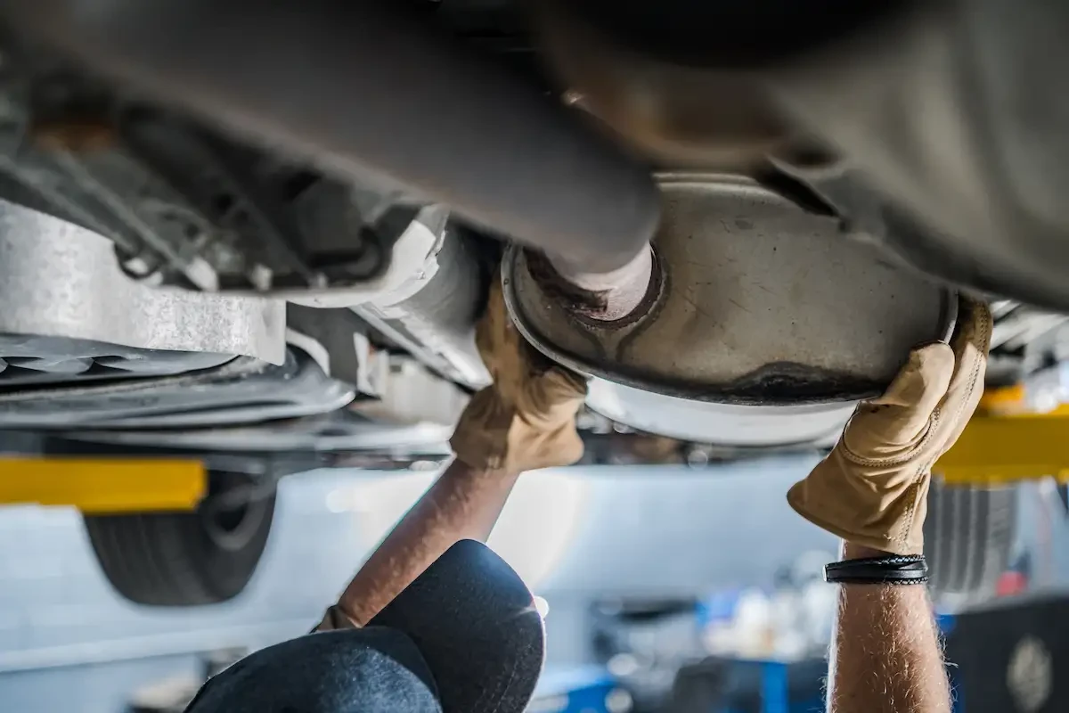 mechanic inspecting a catalytic converter from underneath