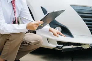 A technician reviews a vehicle damage estimate at a collision repair shop.