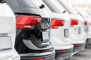Alt text: Close-up of the rear taillights of a row of new SUVs parked at a dealership