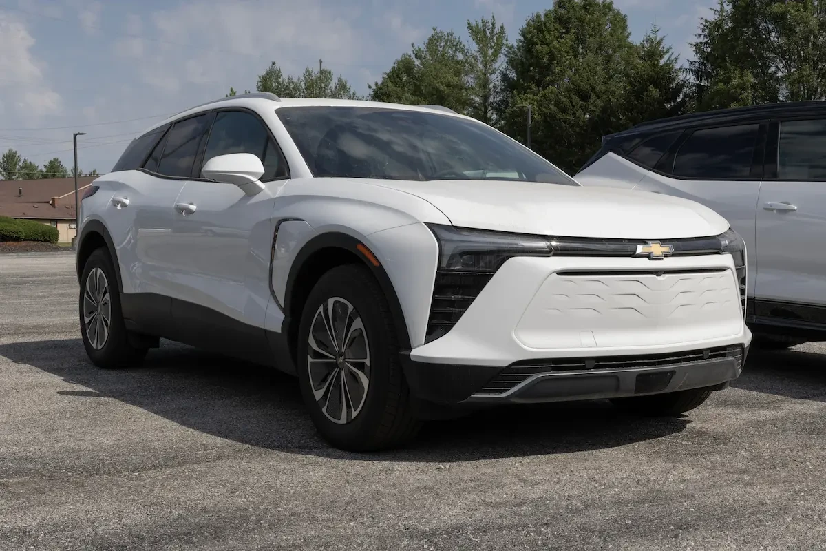 White Chevrolet Blazer EV parked in a lot with trees and another vehicle in the background.