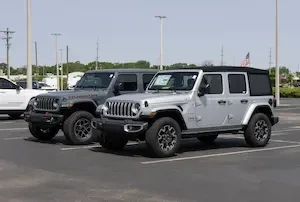 A gray Jeep Gladiator and a silver Jeep Wrangler parked side by side on a car dealership lot.