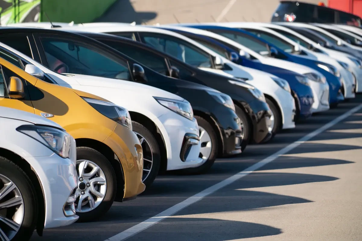 A row of used cars of varying colors parked closely together in a dealership lot.