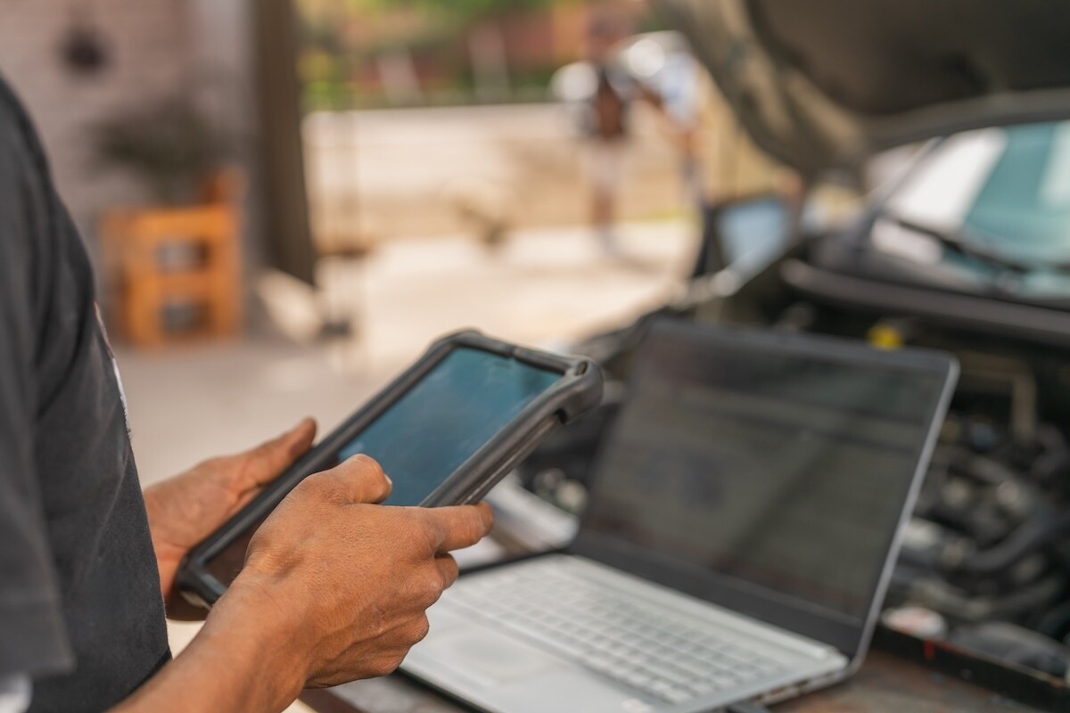 closeup of hands holding a tablet in front of a laptop