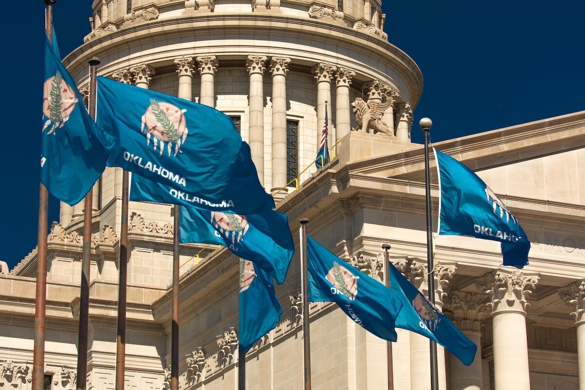 outside the Oklahoma State Capitol with Oklahoma flags