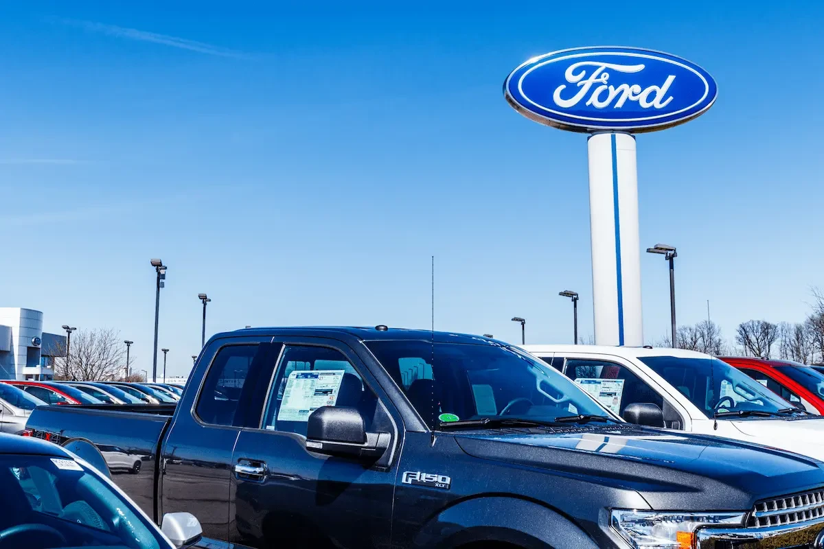 Ford trucks with Ford logo on a sign behind them