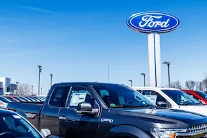 Ford trucks with Ford logo on a sign behind them