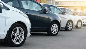 Rows of used vehicles of varying makes and colors parked in an outdoor lot.