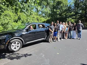 group of people standing by a black car