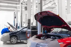 two cars with hoods open in a repair shop