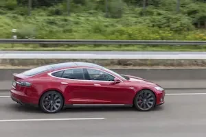 a red Tesla Model S driving