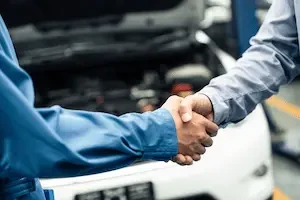 hands shaking in front of a car with open hood