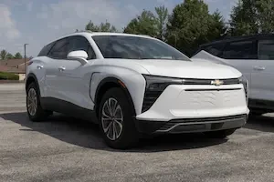 White Chevrolet Blazer EV parked in a lot with trees and another vehicle in the background.