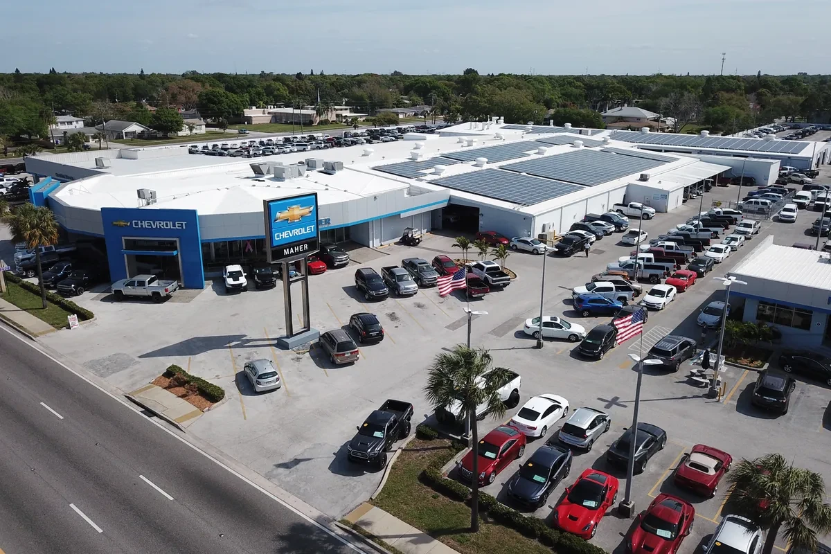 An aerial view of a white and blue car dealership and collision repair shop with a Chevrolet sign