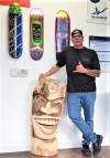 Painter and Technical Director Todd Stogdell poses with one of his tikis and several of his skateboard decks, displayed at Island Concepts, a paint jobber with a training center in Oahu, HI.