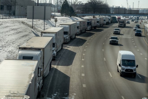 A small line of semi-trailer trucks line up along I-75 in Detroit as the Ambasssador Bridge entrance is blocked off for travel to Canada on Feb. 8.