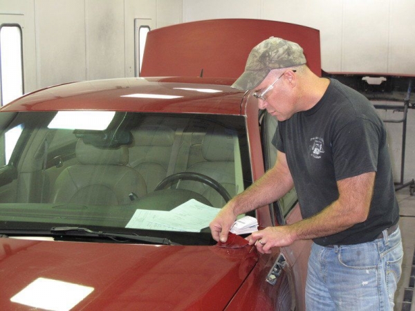 Precision Collision &amp; Auto Glass of Frankfort co-owner Reagan Frixen matches color swatches to a Buick Lucerne.