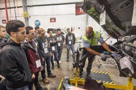  FCA trainer Dedrick Collins shows students how to install parts under the hood at an assembly mock-up at FCA U.S. Warren Assembly Plant on Manufacturing Day. 