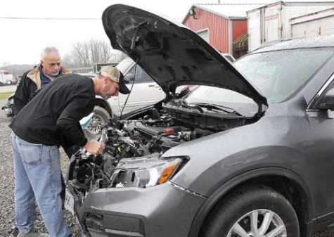 Travis Morgan, right, of B&amp;B Body Shop and Towing, and Frank Bruno, vehicle appraiser for FrontLine Appraisals, check out the heavy damage to the front of this SUV after the driver hit a deer on Interstate 70 the weekend of Nov. 10--11.