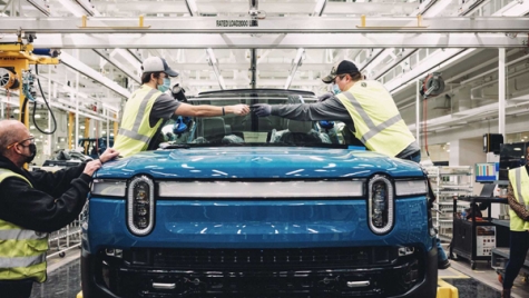 Assembly team members insert a windshield on a Rivian R1T on the production line at Rivian’s plant in Normal, IL.
